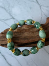 Dreamy Jade bracelet featuring smooth green natural jade beads and polished gold-tone spacers on a wooden display