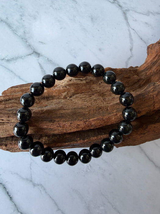 Dreamy Jade black obsidian beaded bracelet with polished round stones on a rustic wooden display