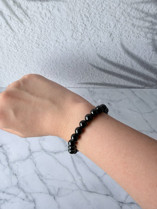 Dreamy Jade black obsidian beaded bracelet on a wrist, featuring polished round stones on a comfortable elastic cord.