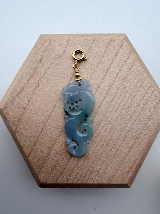 Dreamy Jade carved jadeite dragon pendant with a gold-tone clasp on a wooden display base.