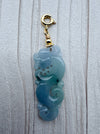 Dreamy Jade blue-green jadeite dragon pendant with a gold-tone clasp on a textured white background