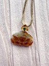 Dreamy Jade pendant necklace featuring a carved amber-toned jade stone with a gold floral accent and green gemstone.