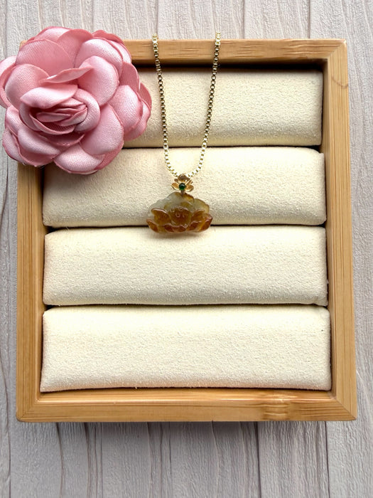 Dreamy Jade necklace with a carved amber-toned jade pendant, gold-tone floral setting, and green gemstone on a chain.