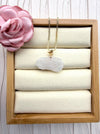 Dreamy Jade elegant white carved jade floral pendant necklace with a gold leaf bail on a gold box chain in a display