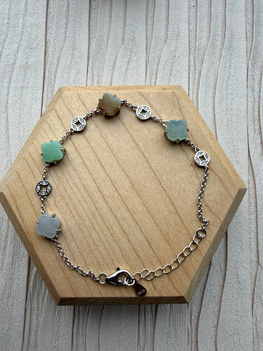 Dreamy Jade multi-coloured jade clover bracelet with 925 sterling silver coin charms on a wooden display stand.