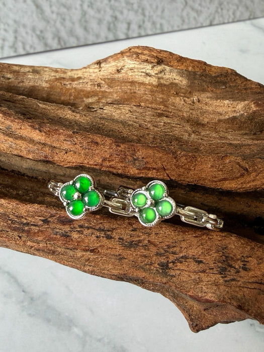 Dreamy Jade clover-inspired rings featuring vibrant green jade stones set in polished silver on a rustic wood background.