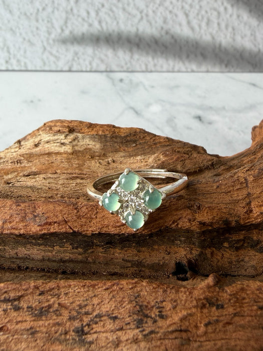 Dreamy Jade clover-inspired ring featuring four mint green jade stones set in polished silver on a rustic wood base.