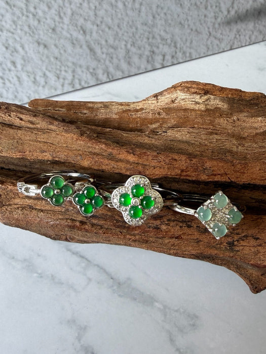 Dreamy Jade clover-inspired rings featuring green jade stones set in polished silver on a rustic wooden display.