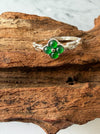 Dreamy Jade clover ring featuring vibrant green jade stones set in polished silver on a rustic wooden background.