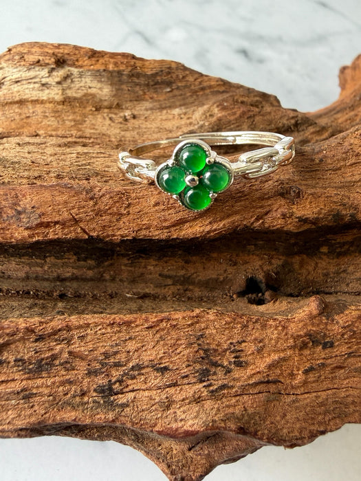 Dreamy Jade clover ring featuring vibrant green jade stones set in polished silver on a rustic wooden background.