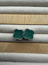Dreamy Jade clover stud earrings featuring green stone inlay and a delicate beaded metal border on a velvet tray.