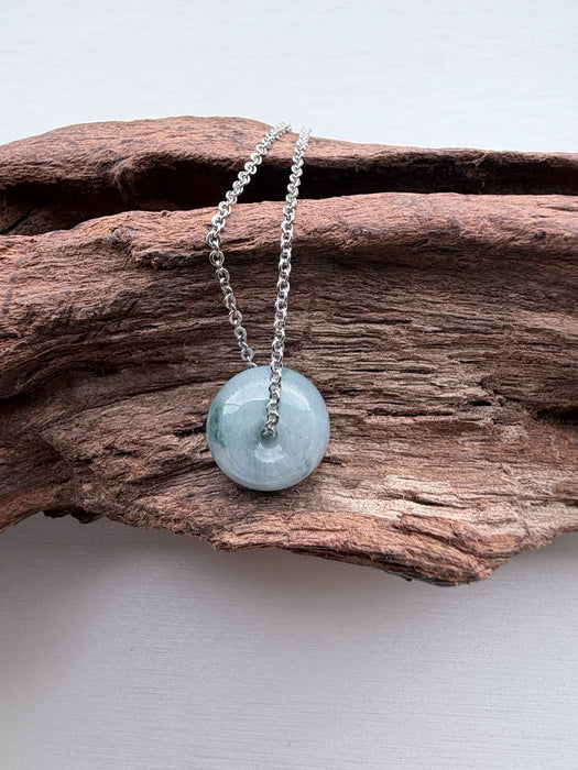 Dreamy Jade donut pendant necklace featuring a translucent green polished jade stone on a silver-tone chain.