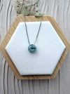 Dreamy Jade donut pendant necklace featuring a translucent green jade stone on a silver-tone chain on a display stand.