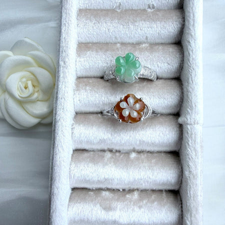Dreamy Jade floral rings featuring carved green and amber jade petals on polished silver-tone bands in a velvet tray.