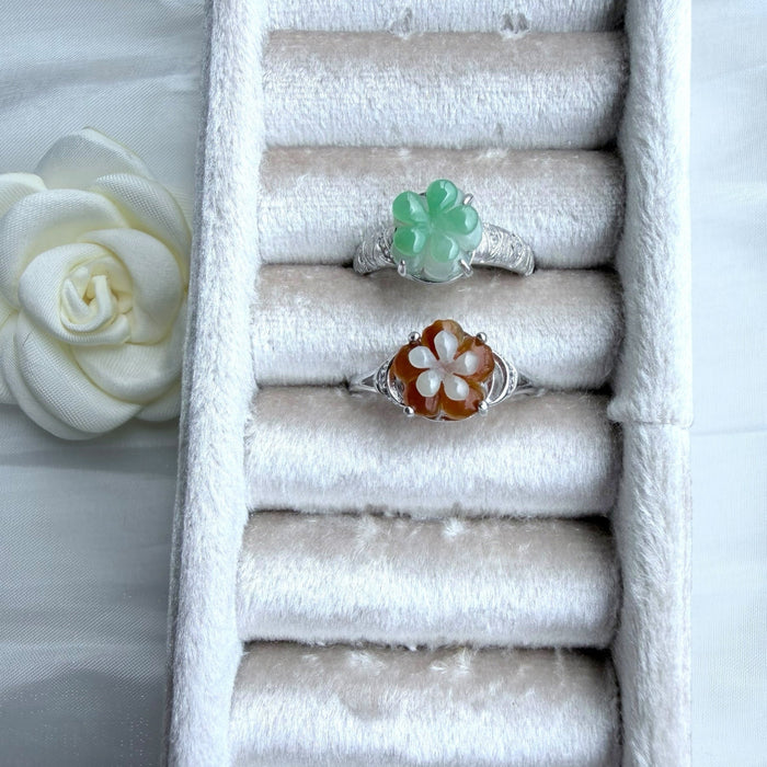 Dreamy Jade floral rings featuring carved green and amber jade petals on polished silver-tone bands in a velvet tray.