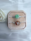 Dreamy Jade floral rings featuring carved green and amber jade petals on polished silver-tone bands in a velvet box.
