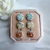Dreamy Jade floral stud earrings with gemstone centres and crystal halos in green, yellow, and orange on velvet tray.