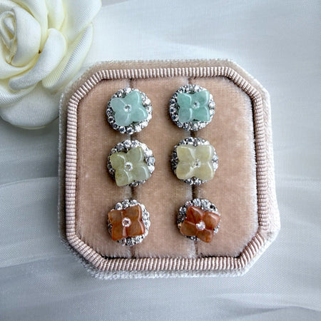 Dreamy Jade floral stud earrings with gemstone centres and crystal halos in green, yellow, and orange on velvet tray.