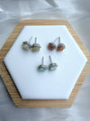 Dreamy Jade floral stud earrings with gemstone centres and crystal halos on a white hexagonal display stand