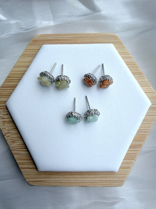 Dreamy Jade floral stud earrings with gemstone centres and crystal halos on a white hexagonal display stand