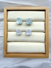 Dreamy Jade floral stud earrings with carved pale green and white jade petals and a central stone in a wooden tray