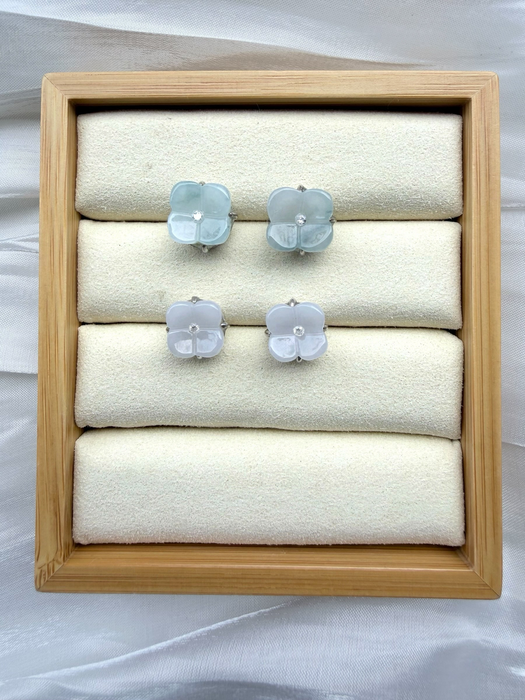 Dreamy Jade floral stud earrings with carved pale green and white jade petals and a central stone in a wooden tray