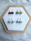 Dreamy Jade floral stud earrings in red, yellow, icy white, and mint green jade set in polished metal on a display.