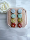 Dreamy Jade floral stud earrings in icy white, mint green, golden yellow, and sunset red on a velvet display box.