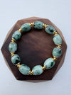 Dreamy Jade beaded bracelet featuring smooth green natural jade stones and polished gold-tone spacers on wood display
