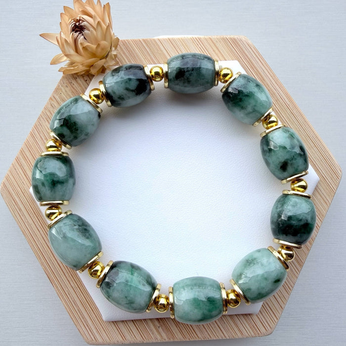 Dreamy Jade beaded bracelet with polished green natural jade stones and gold-tone spacers on a wooden display stand.