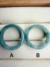 Dreamy Jade pair of polished natural green jadeite stone bangles with unique marbling on a beige jewellery tray