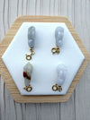 Dreamy Jade hand-carved rabbit charms in genuine jade with gold-tone clasps on a white hexagonal display stand.