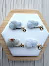 Dreamy Jade hand-carved rabbit charms in various shades of natural jade with gold-tone clasps on a hexagonal display