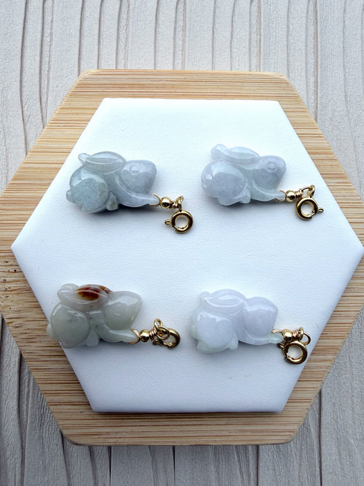 Dreamy Jade hand-carved rabbit charms in various shades of natural jade with gold-tone clasps on a hexagonal display