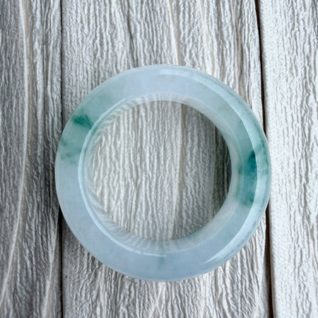 Dreamy Jade natural jadeite ring with translucent icy base and vibrant green splashes on a textured white background.