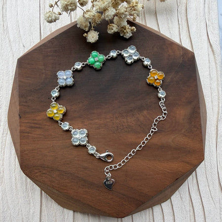 Dreamy Jade multi-coloured clover bracelet with polished jade stones set in 925 sterling silver on a wooden base.