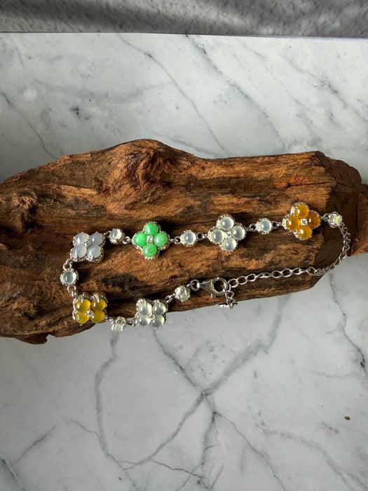 Dreamy Jade multi-coloured jade clover bracelet in 925 sterling silver resting on a piece of natural wood