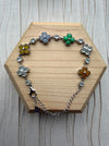 Dreamy Jade multi-coloured clover bracelet with polished gemstone motifs set in 925 sterling silver on a wooden base.
