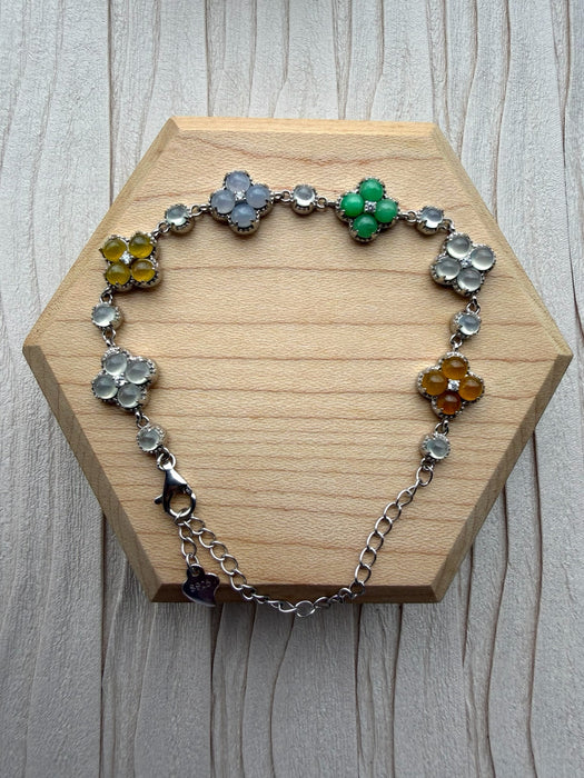 Dreamy Jade multi-coloured clover bracelet with polished gemstone motifs set in 925 sterling silver on a wooden base.