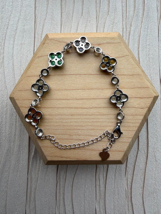 Dreamy Jade sterling silver bracelet featuring multi-coloured jade four-leaf clover motifs on a wooden display base.