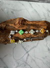 Dreamy Jade multi-coloured jade clover bracelet in 925 sterling silver resting on a piece of natural driftwood.
