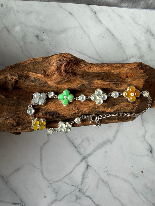 Dreamy Jade multi-coloured jade clover bracelet in 925 sterling silver resting on a piece of natural driftwood.