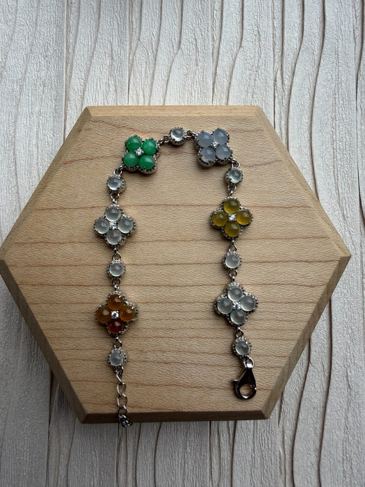 Dreamy Jade multi-coloured clover bracelet with polished jade stones set in 925 sterling silver on a wooden display.