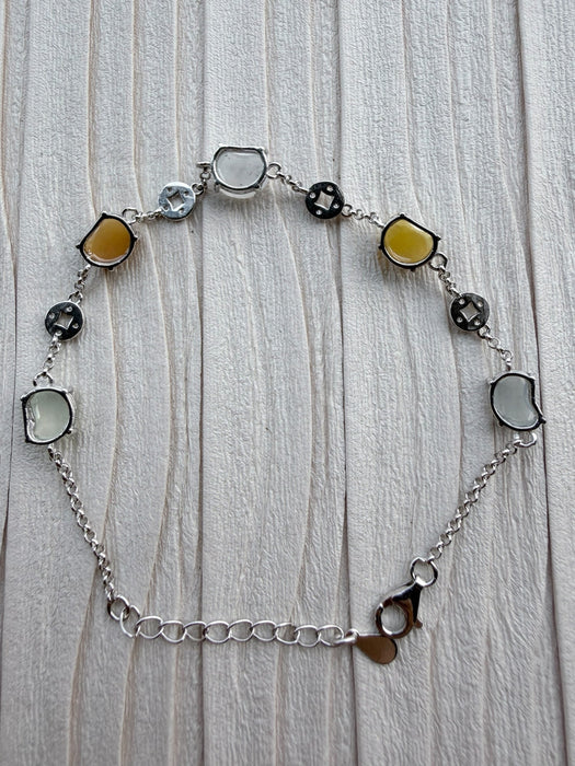 Dreamy Jade multi-coloured jade and 925 sterling silver link bracelet with coin-inspired charms on a textured surface