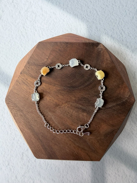 Dreamy Jade multi-coloured jade and 925 sterling silver coin charm link bracelet on a wooden display base.