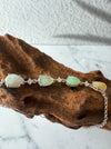Dreamy Jade multi-coloured jade and sterling silver link bracelet with cubic zirconia accents on a wooden display