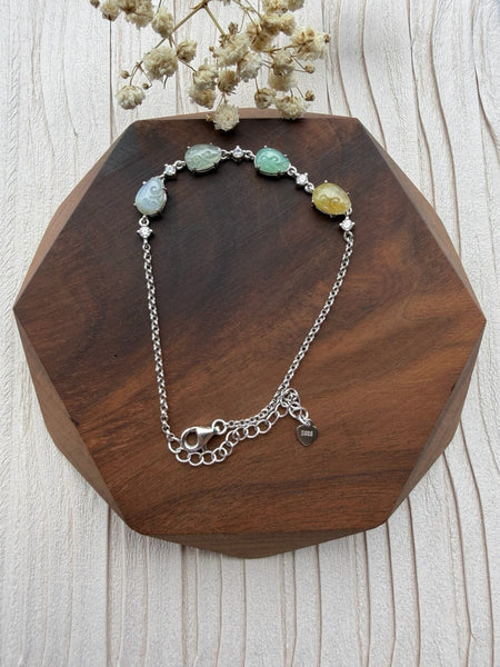 Dreamy Jade multi-coloured jade and sterling silver link bracelet with cubic zirconia accents on a wooden display.