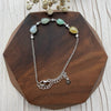 Dreamy Jade multi-coloured jade and sterling silver link bracelet with cubic zirconia accents on a wooden display.