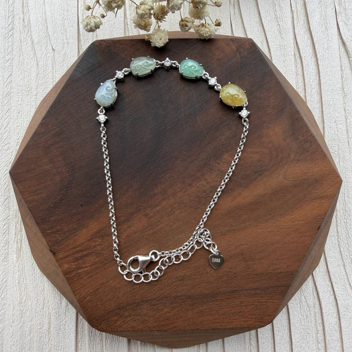 Dreamy Jade multi-coloured jade and sterling silver link bracelet with cubic zirconia accents on a wooden display.