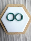 Dreamy Jade pair of polished natural green jadeite bangles with unique marbling on a white hexagonal display stand